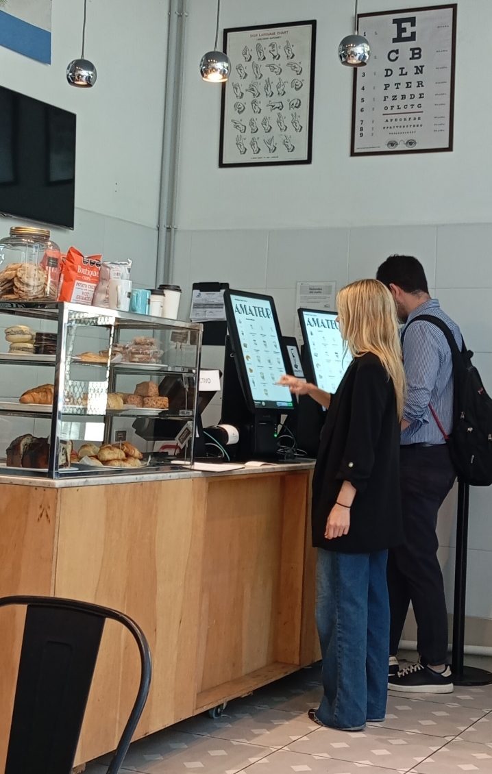 Cliente usando un tótem de autoservicio OrderFast en un local gastronómico