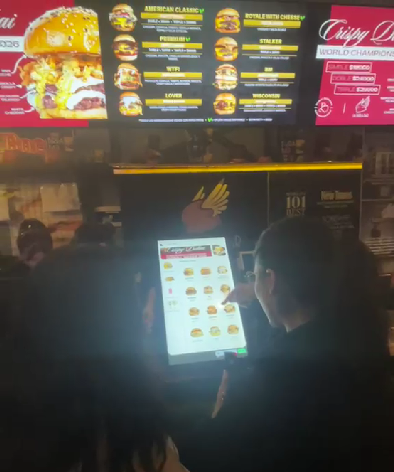 Cliente usando un tótem de autoservicio OrderFast en un local de comidas